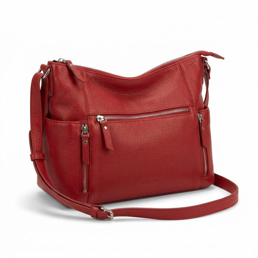 Detailed high-resolution product photography of the Mancini June Crossbody Bag (HBP1081-RED) in premium red pebble-grain leather on a clean white background. Centered composition, silver hardware details, and an embossed logo visible on the front. Includes a detachable crossbody strap.