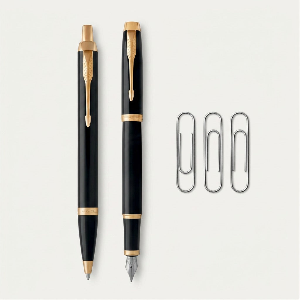 A Parker IM fountain pen and ballpoint pen set in black and gold next to paperclips for scale.