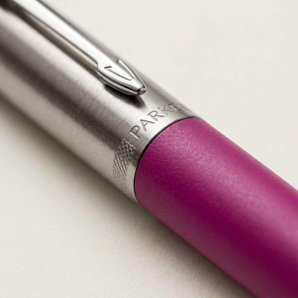 Macro view of Parker Jotter pen showing stainless steel cap, arrow clip, and magenta barrel texture.